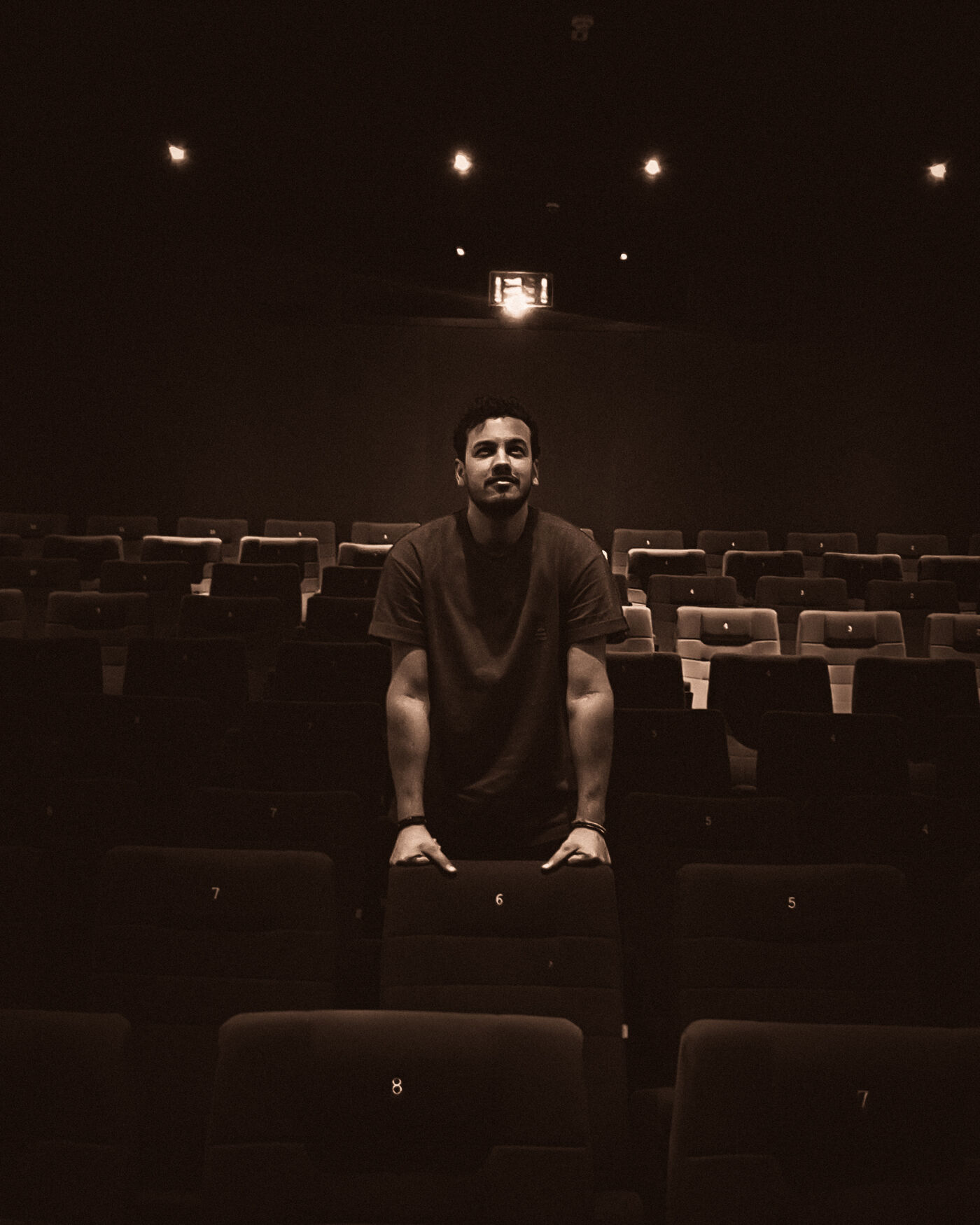 Mohammed alone in an empty cinema, looking up at the projector light
